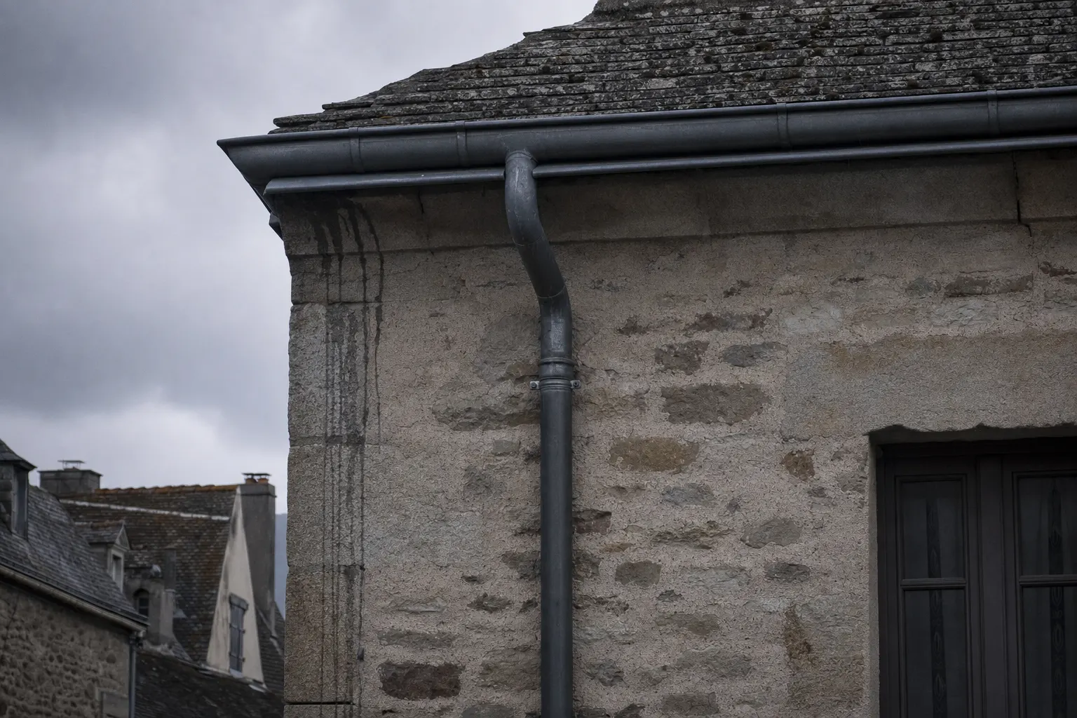 Gouttière et descente en zinc le long d'une façade en pierre