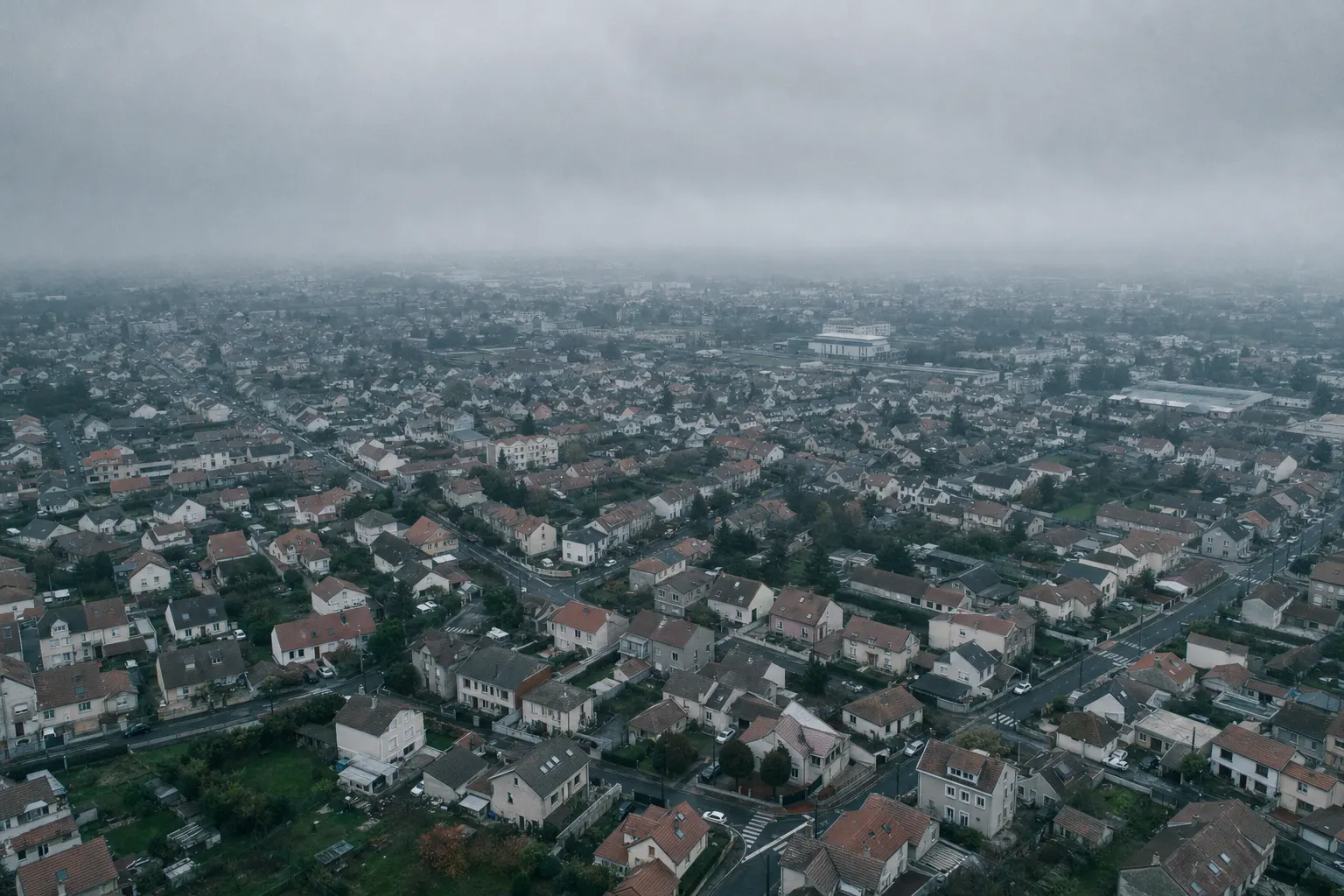 Vue aérienne d'un quartier pavillonnaire aux toitures en tuile sous ciel gris